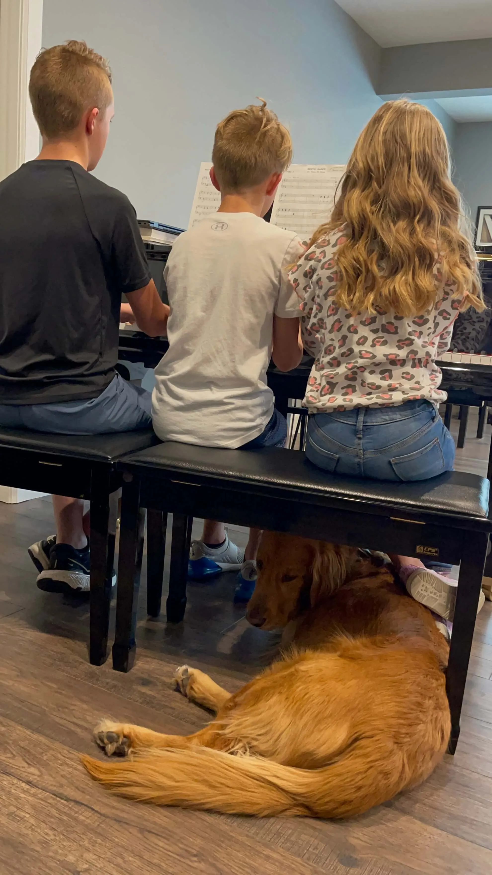 three kids at piano with ollie under bench
